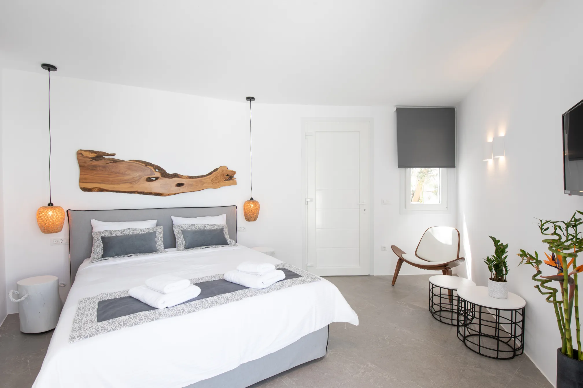 Bed with a grey linen runner facing the wardrobe and TV